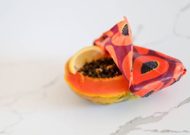 Half-cut papaya with a colorful butterfly on a white marble surface