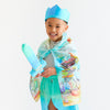Child wearing a costume with a blue crown and colorful scarf on a white background