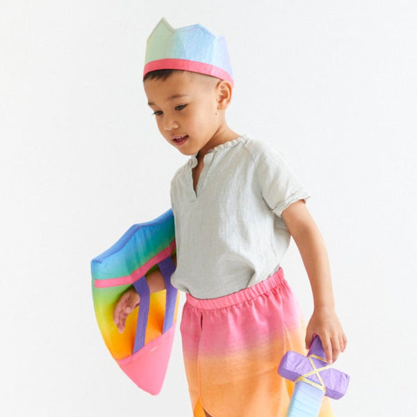Child wearing a colorful hat and holding a rainbow-colored toy on a white background