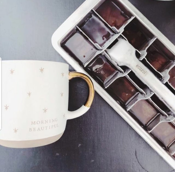 Box of chocolates next to a mug with 'Morning Beautiful' text on a gray surface