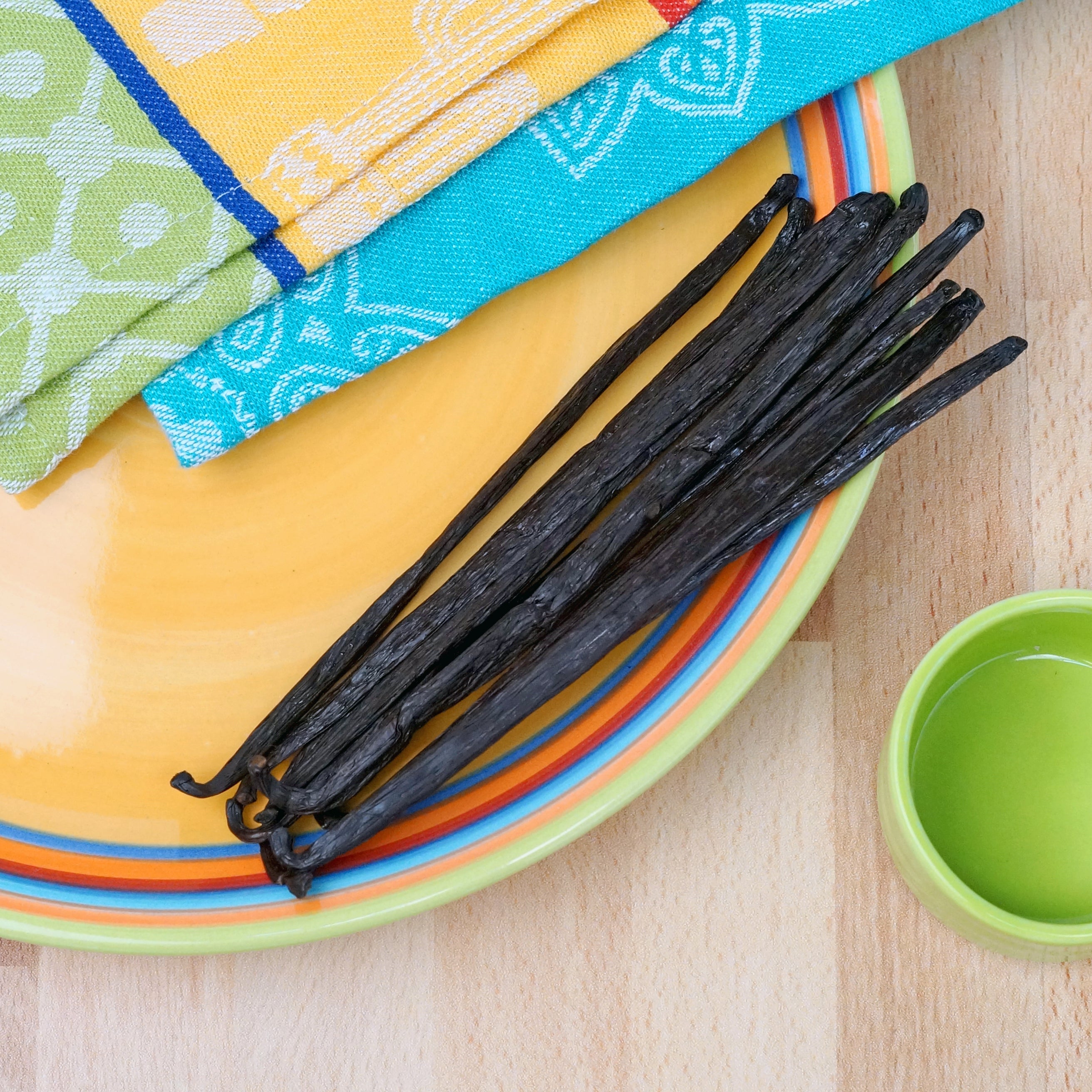 Vanilla beans on a colorful plate with a wooden background