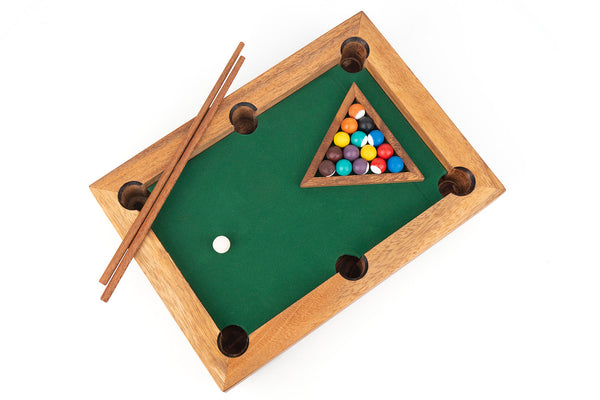 Miniature pool table with balls and cues on a white background