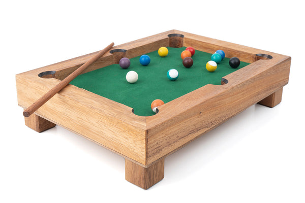 Miniature pool table with balls and a cue on a white background