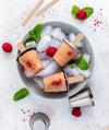 Popsicles on a plate with ice and berries on a light background