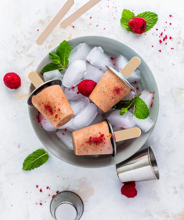 Popsicles on a plate with ice and berries on a light background