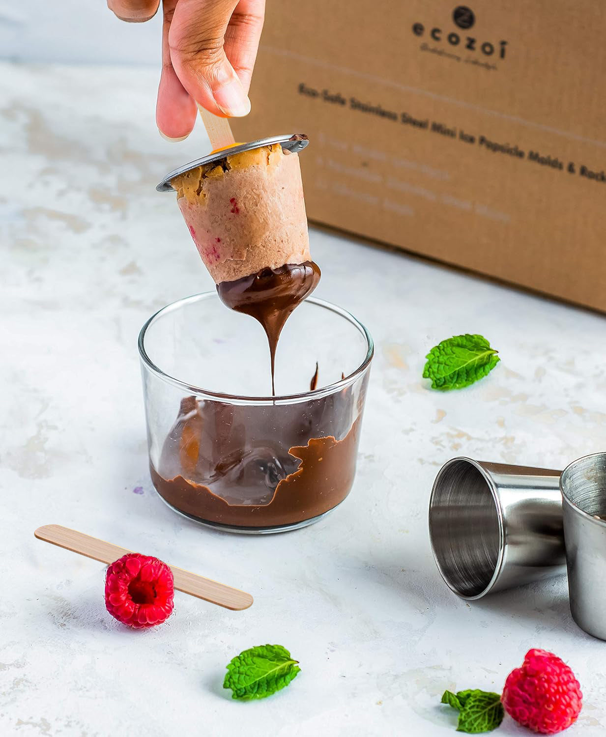 Dipping a popsicle into chocolate with ecozai packaging in the background