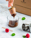 Dipping a popsicle into chocolate with ecozai packaging in the background