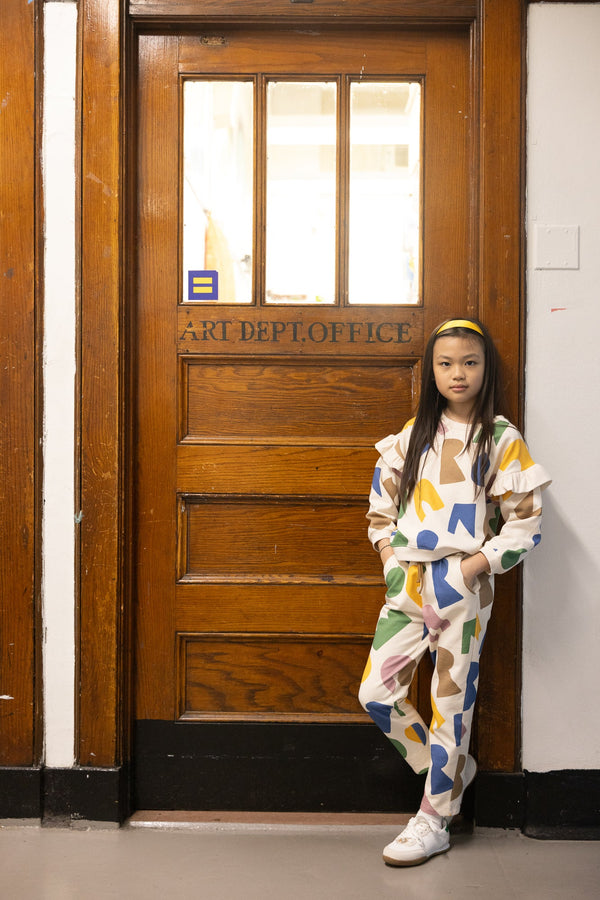 Child in a colorful outfit standing in front of a wooden door with 'Art Dept Office' text.