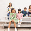 Children sitting on a bench wearing colorful clothing