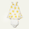 White baby dress with yellow sun patterns and white bloomers on a light beige background