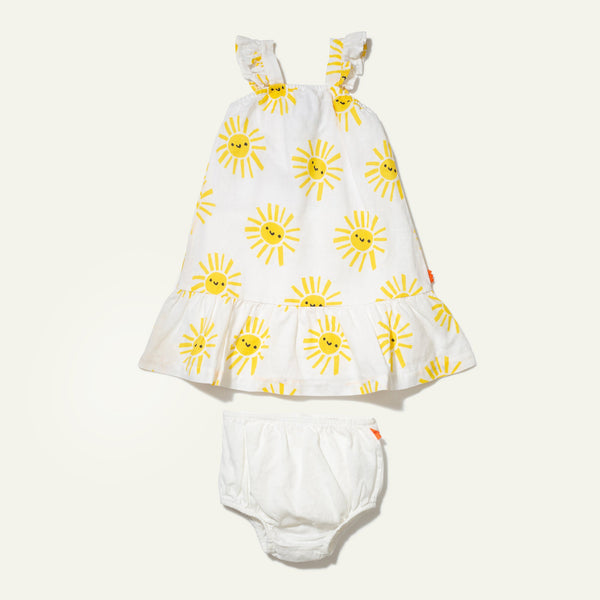 White baby dress with yellow sun patterns and white bloomers on a light beige background