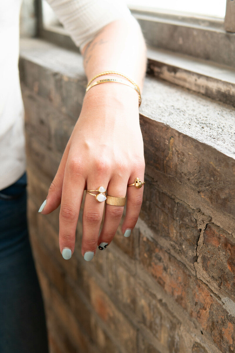 Close-up of the Stately Striped Brass Ring alongside other sustainable brass rings from the India Collection