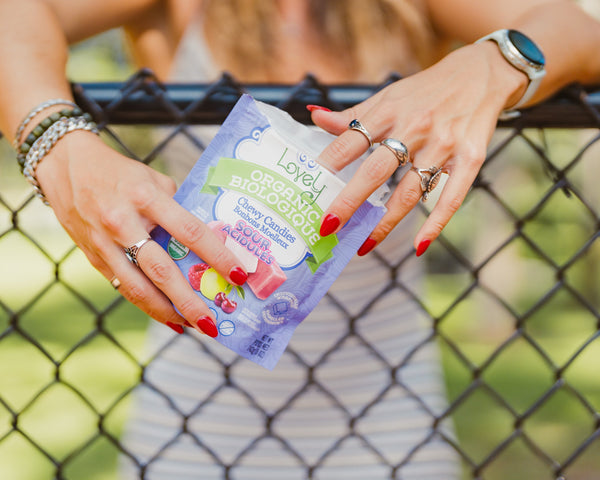 Person holding a package of 'Lovely' organic snacks with a blurred background