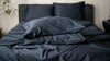 Dark blue bedding set on a bed with pillows and duvet