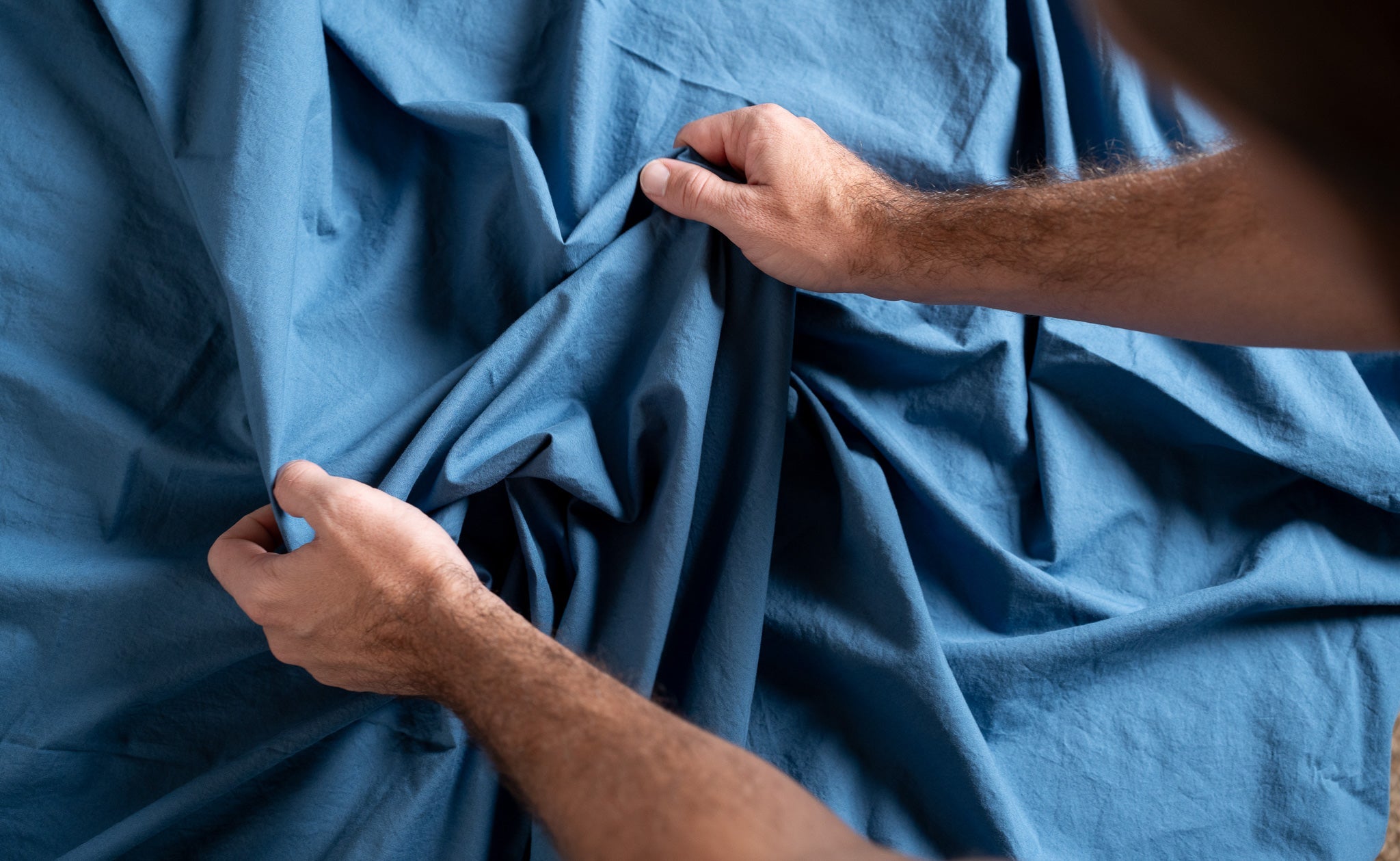 Person holding blue fabric with visible skin texture