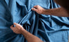 Person holding blue fabric with visible skin texture