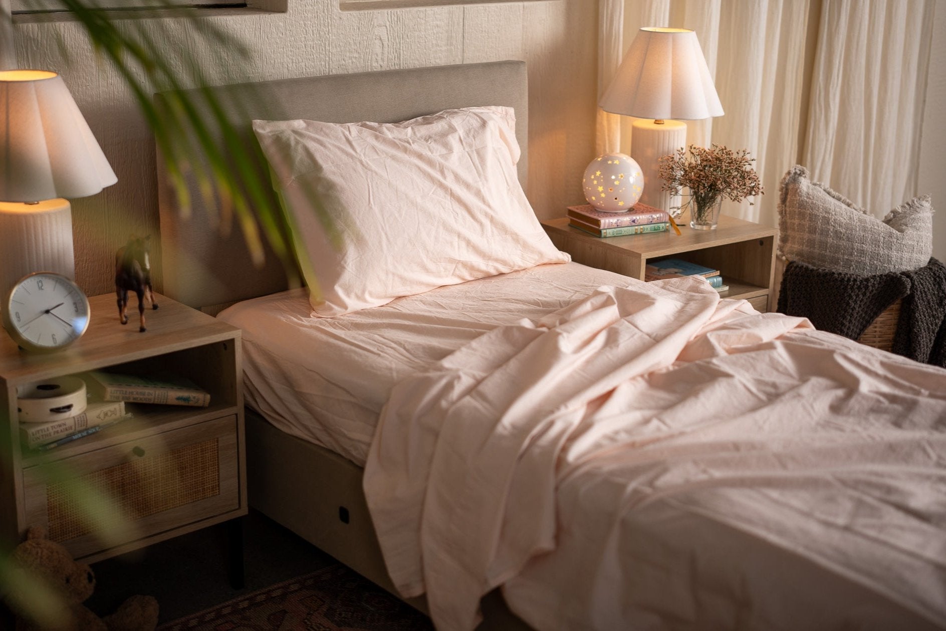 Neatly made bed in a bedroom with two lamps and a clock on nightstands.