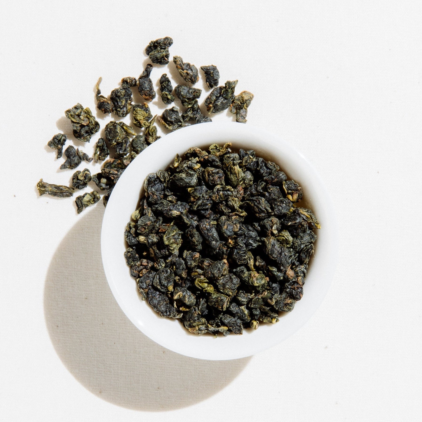 Orchid Oolong loose leaf tea rolled into kernels in a white bowl, sourced from Nantou, Taiwan