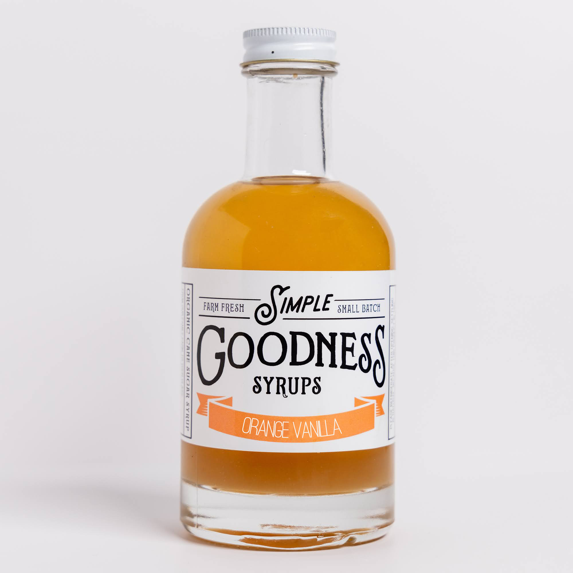 A bottle of Simple Goodness Syrups, Orange Vanilla flavor, in a clear glass bottle with amber liquid, a white label, and a silver cap, set against a plain light gray background.