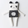 Black and white panda plush toy with a polka dot apron on a light gray background