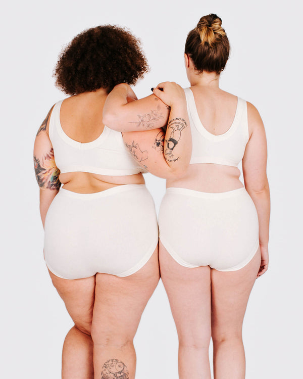 Two people wearing white tank tops and shorts from behind on a plain background