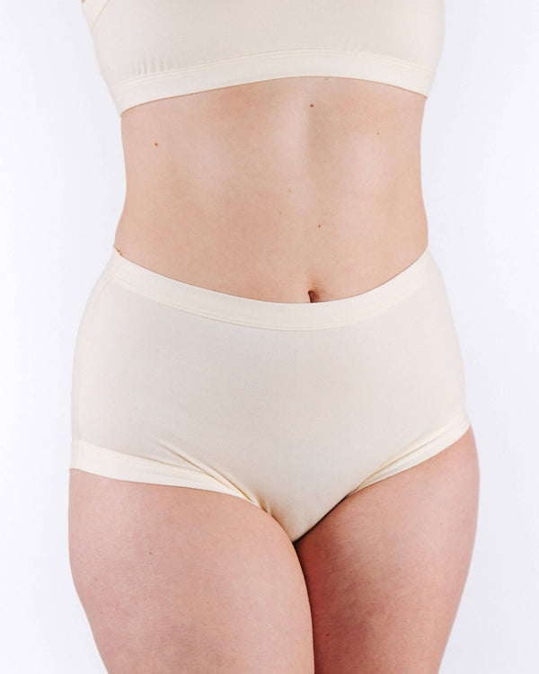 Person wearing a cream-colored bra and panties set on a white background