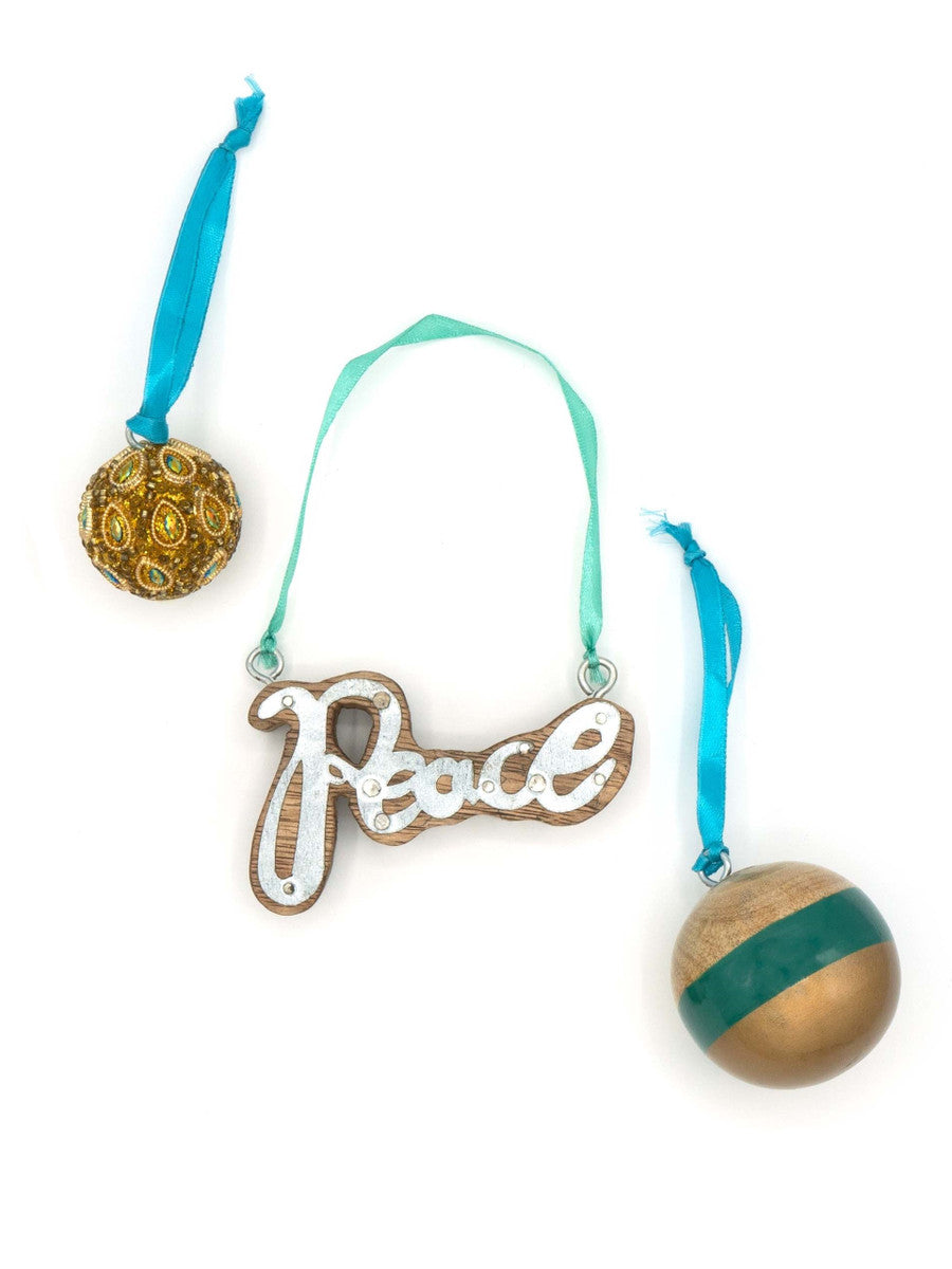 Set of 3 handmade holiday ornaments including peace symbol, painted round, and beaded ornament on a white background