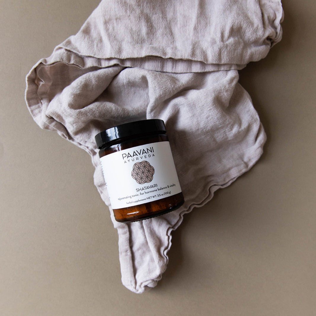 Jar of Paavani Ayurveda product on a beige fabric background