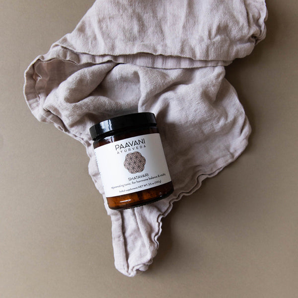 Jar of Paavani Ayurveda product on a beige fabric background