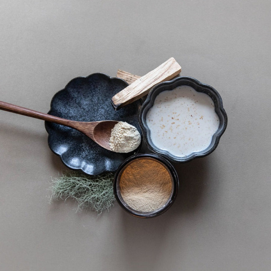 Three black ceramic bowls with wooden spoons on a gray background