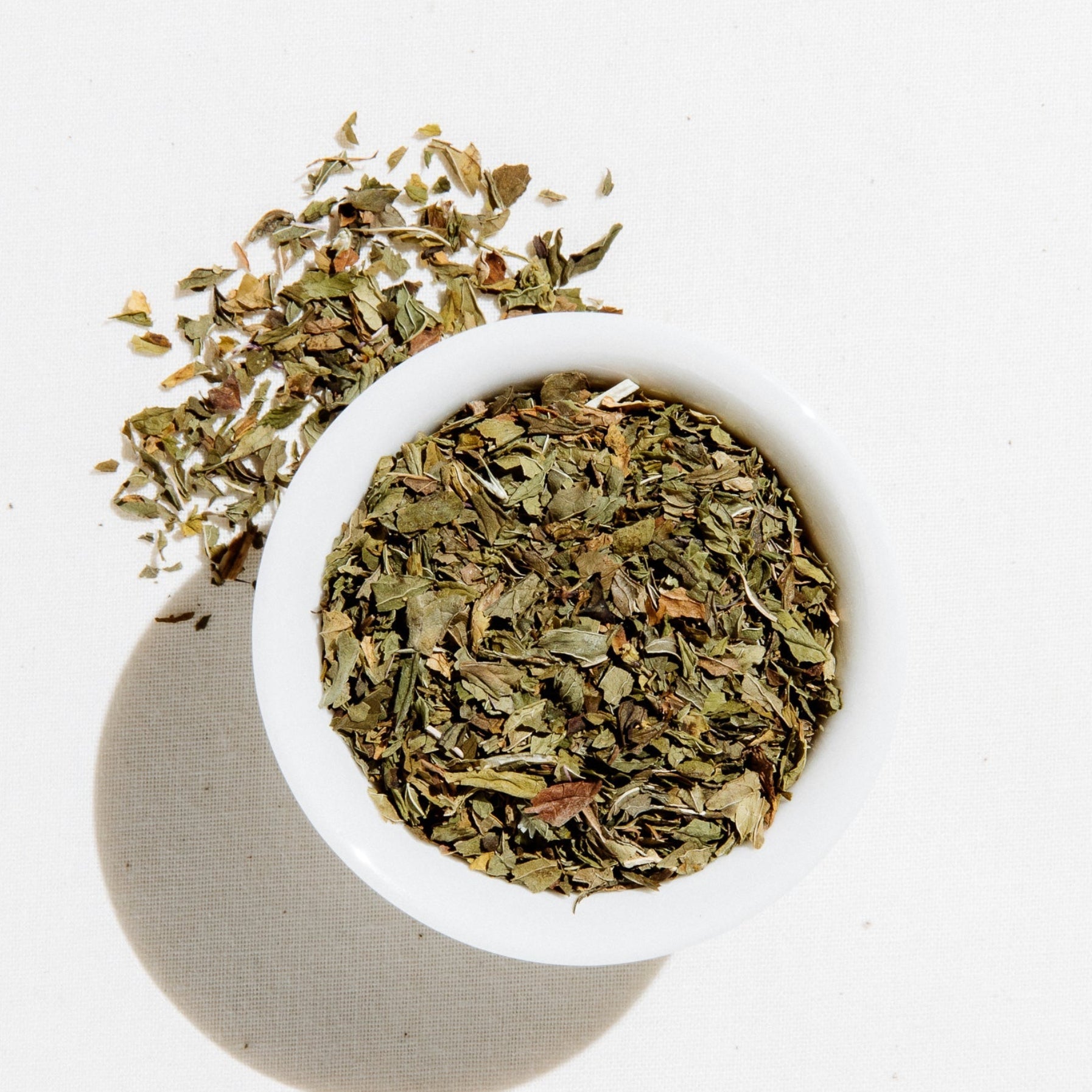 Dried organic spearmint and peppermint leaves in a white bowl, used to make Pacific Coast Mint Tea by Art of Tea