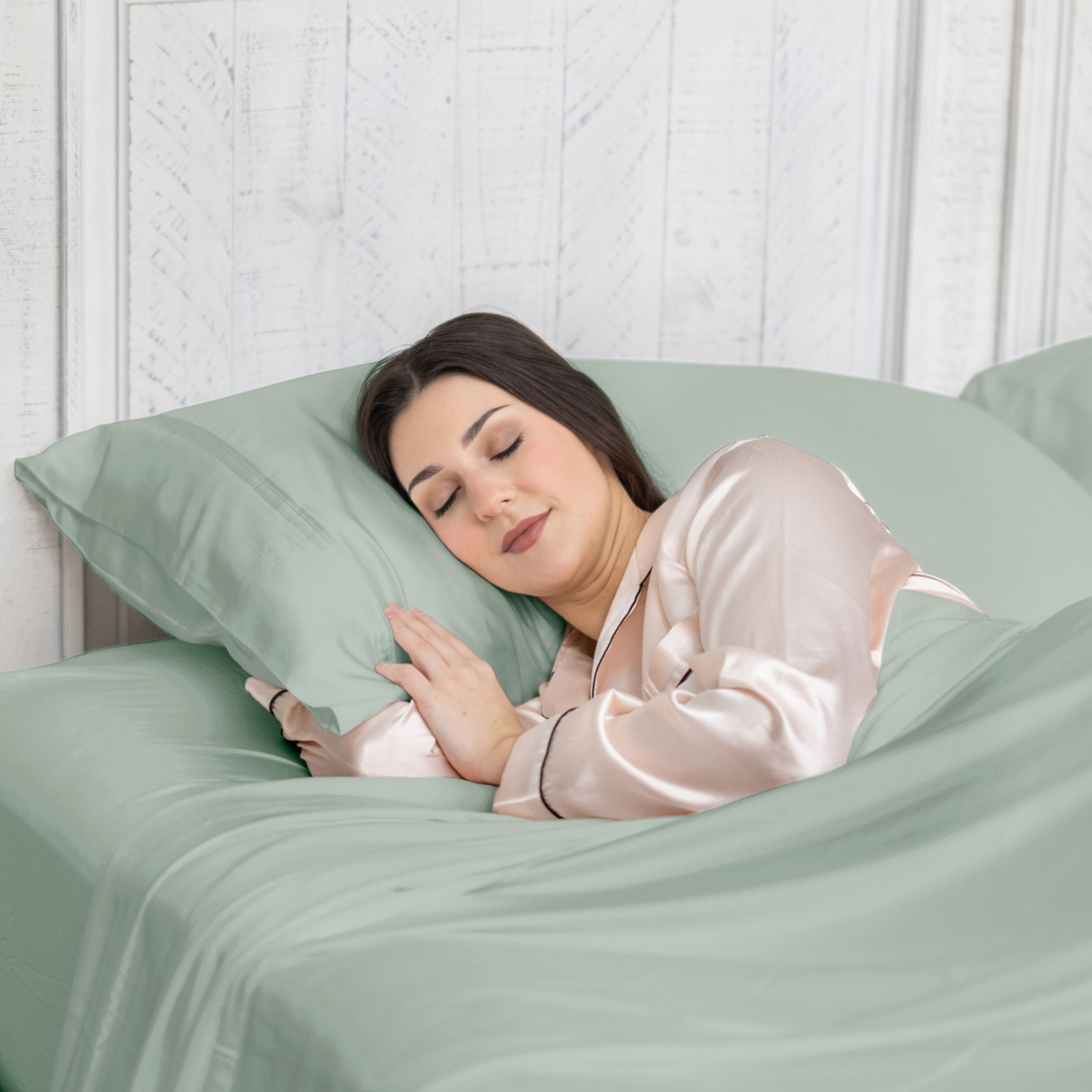 Woman sleeping peacefully in a bed with green bedding and pillow.