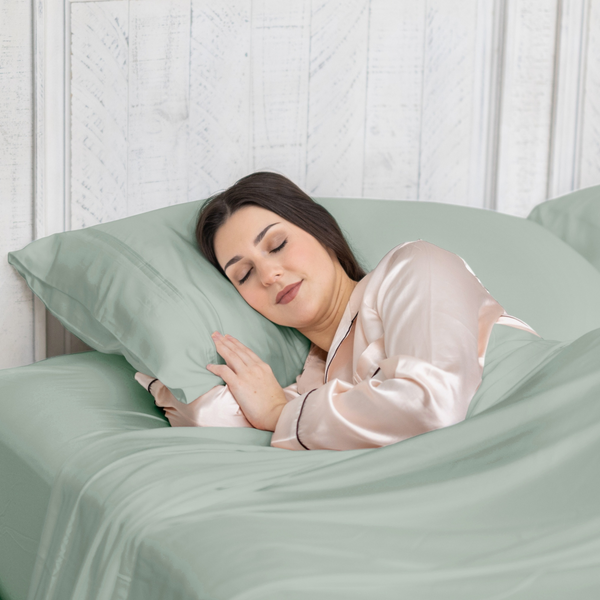 Woman sleeping peacefully in a bed with green bedding and pillow.