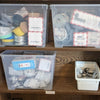 Clear plastic storage bins on a wooden shelf with various items inside.