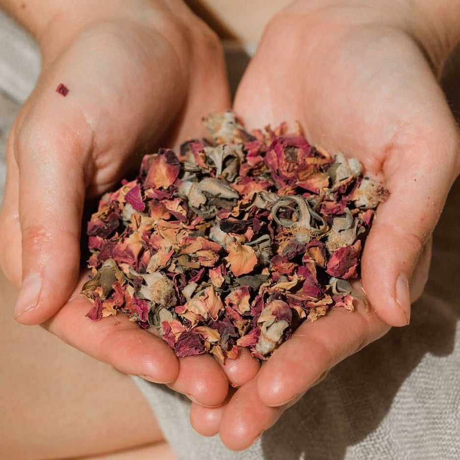 Hands holding a small pile of dried flowers and herbs