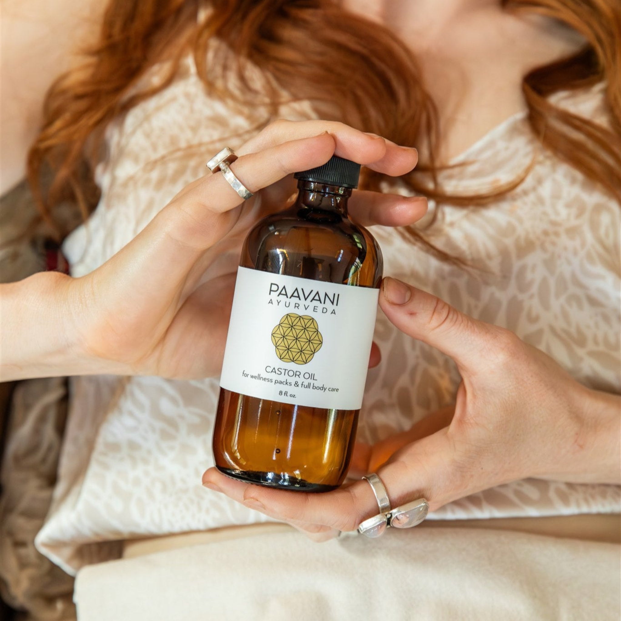 Person holding a bottle of Paavani Ayurveda Castor Oil with a blurred background