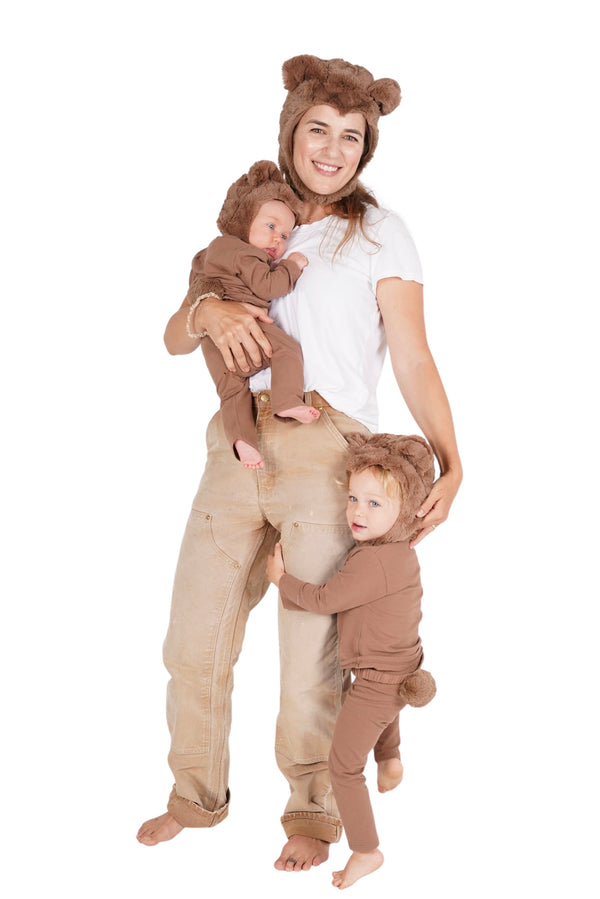 Woman in a bear costume holding two children in matching bear outfits on a white background