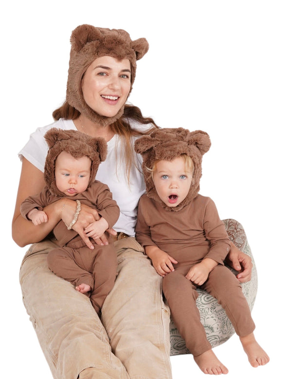 Woman and two children in bear costumes sitting on a chair.