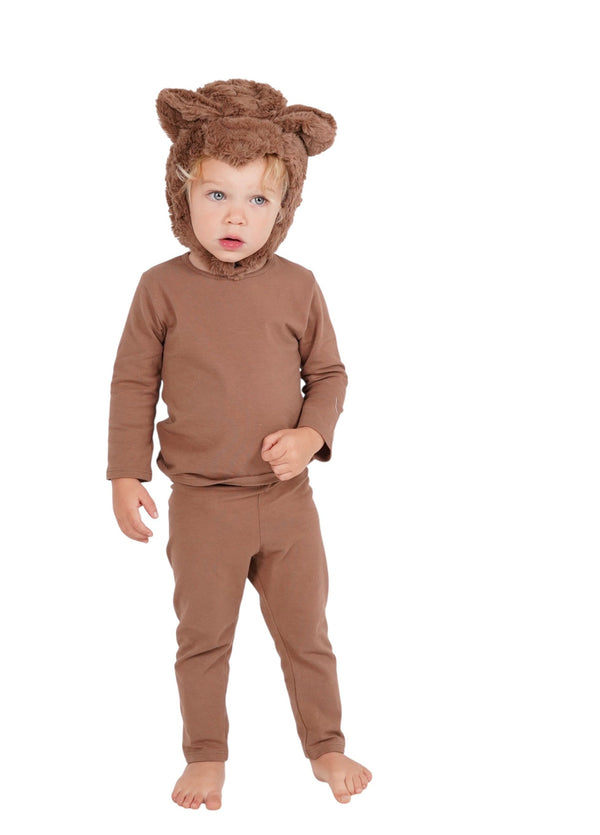 Child wearing a brown bear costume with a hat on a white background