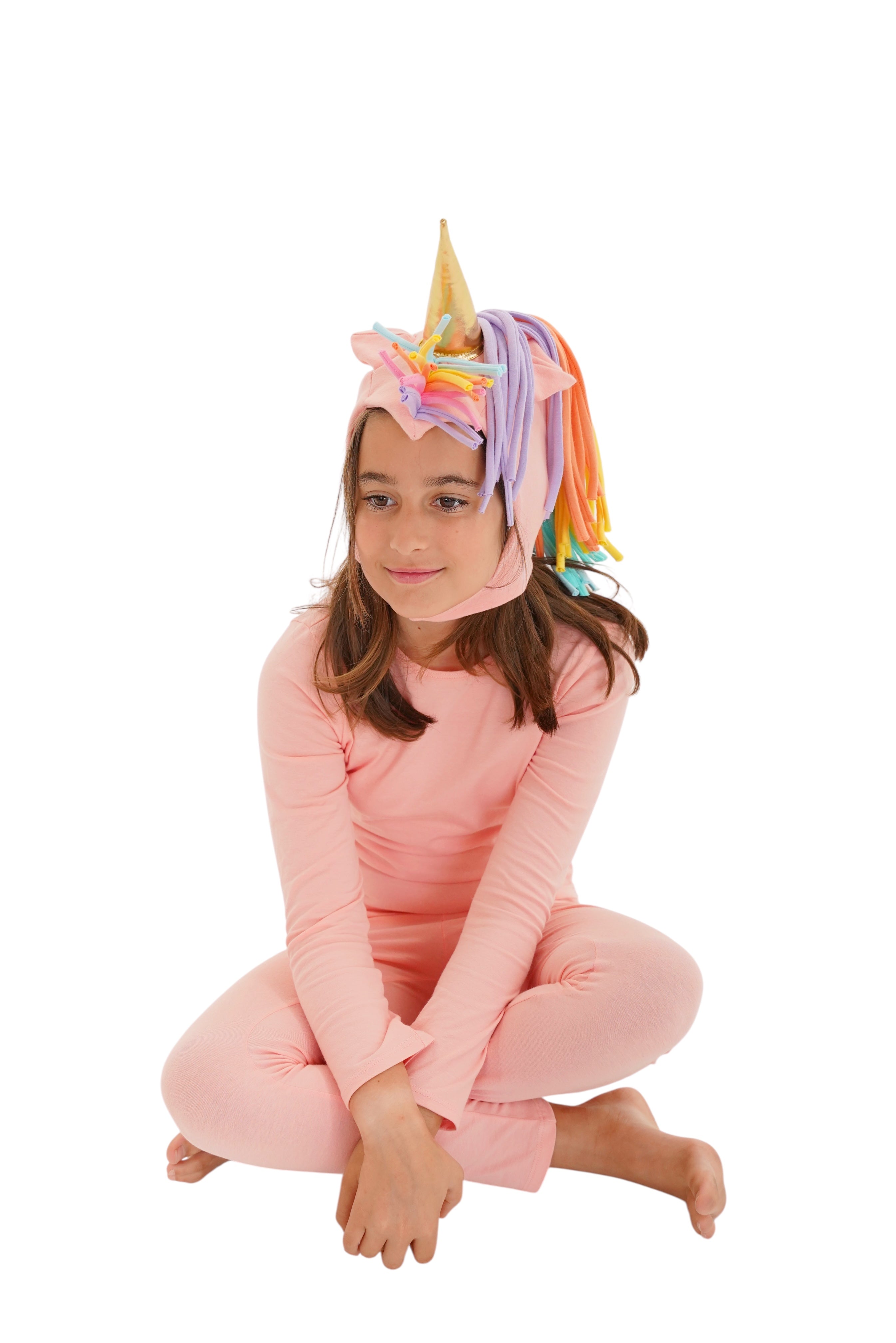 Child wearing a pink unicorn costume with a colorful mane and horn on a white background