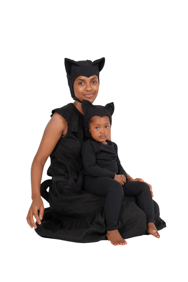 Two people in black cat-themed costumes sitting together on a white background