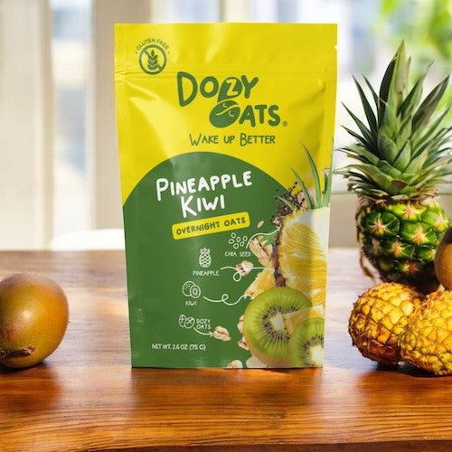 Doley Oats Pineapple Kiwi overnight oats package on a wooden surface with a pineapple and kiwi.