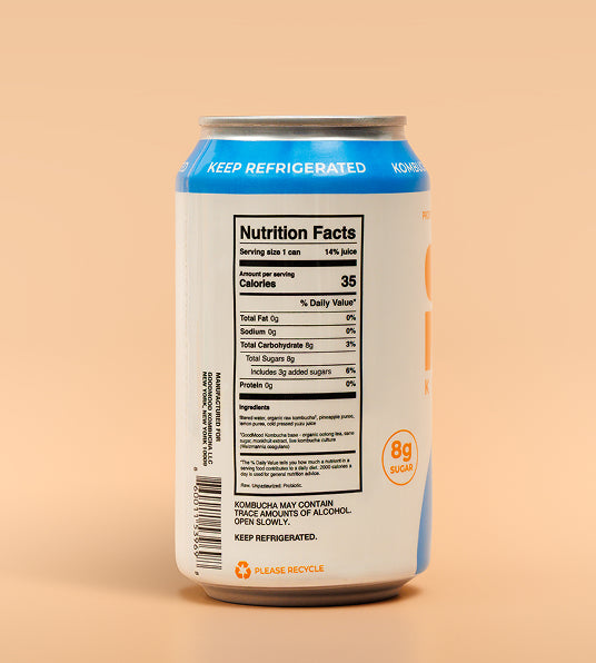A can of kombucha shown from the back, displaying the nutrition facts label, barcode, and a blue 'KEEP REFRIGERATED' band, set against a solid peach background.