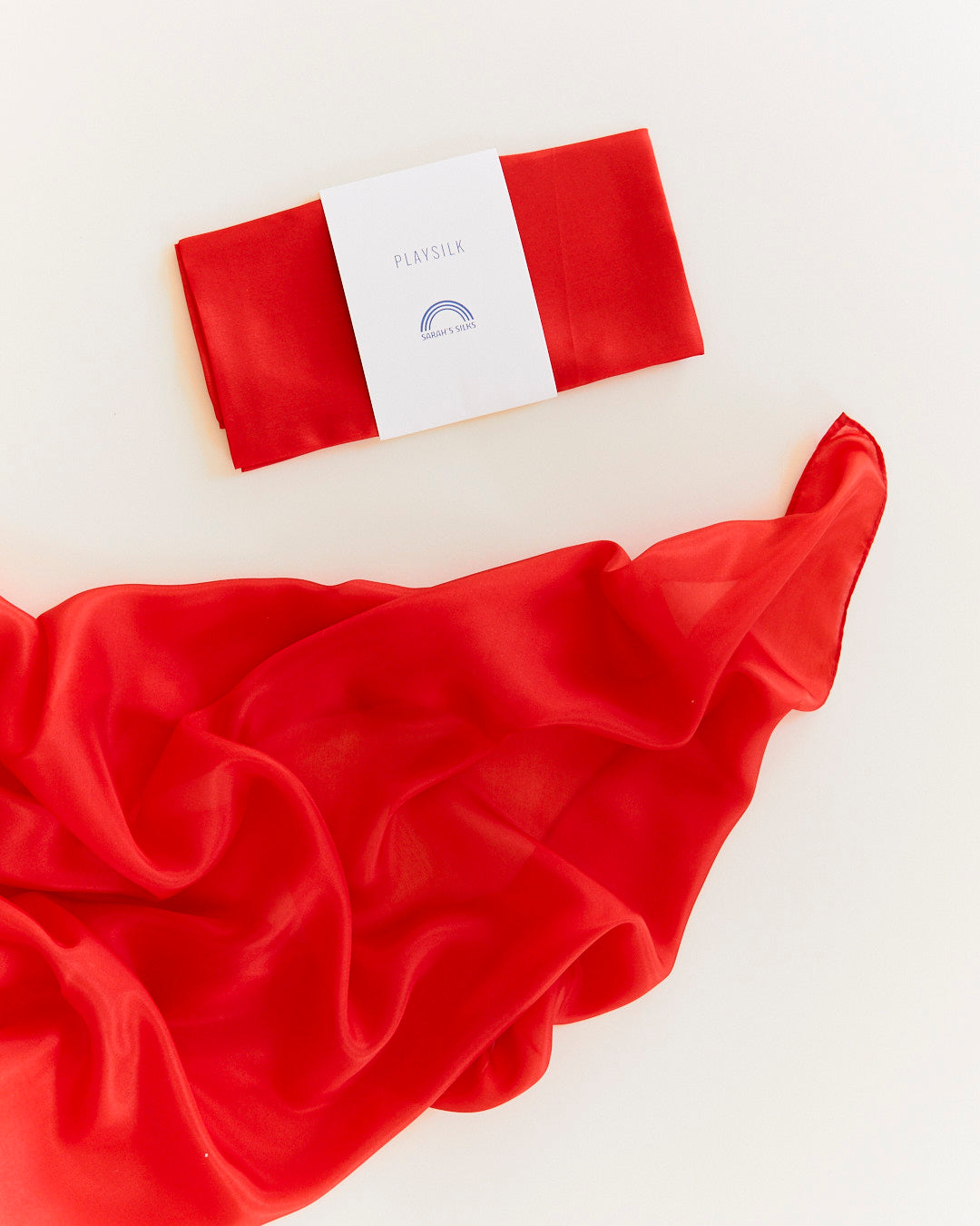 Red satin fabric with a white label on a light beige background