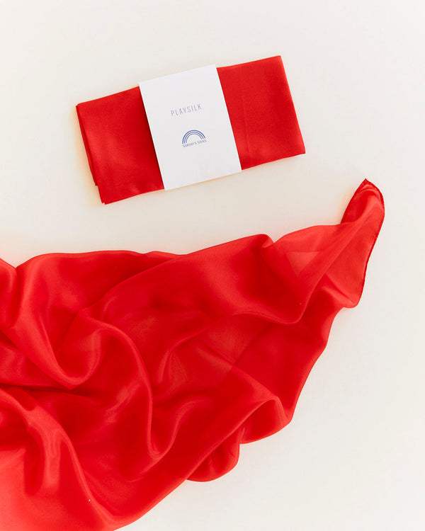 Red satin fabric with a white label on a light beige background