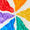 Child playing with colourful Sarah's Silks eco-friendly playsilks in primary colours