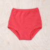 Red high-waisted underwear on a textured beige surface