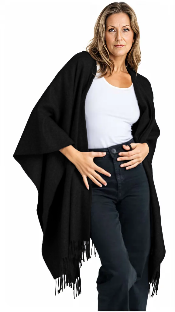Woman wearing a black fringed poncho over a white top and jeans on a white background