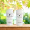 Two bottles of Freedom Natural Deodorant on a wooden surface with a natural background