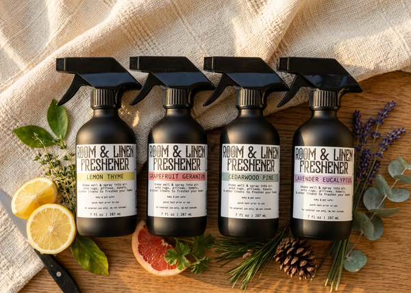 Four matte black Room & Linen Freshener spray bottles by Apotheke DuJardin in Lemon Thyme, Grapefruit Geranium, Cedarwood Atlas & Pine Scots, and Lavender Eucalyptus essential oil blends